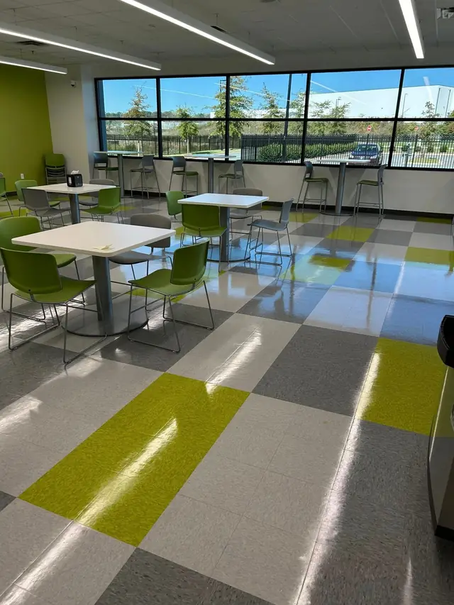 Office break room with a green and grey checkerboard VCT floor and cafe tables