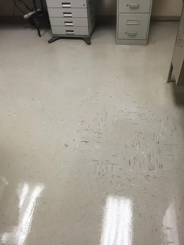 Office floor part way through a strip, with scuffed tile and filing cabinets