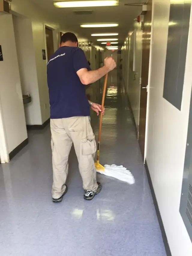 Crew member mopping an institutional corridor floor