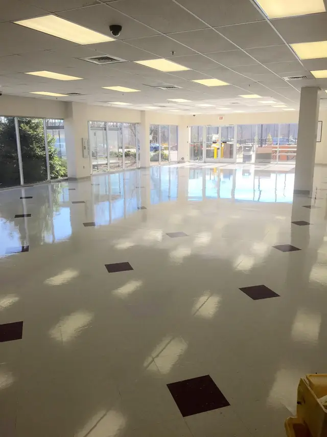 A polished lobby floor with a dark accent tile inlay beside a glass curtain wall