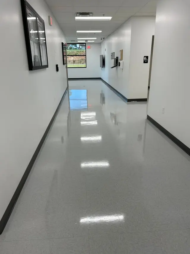 A polished corridor floor photographed close in, with restroom signage on the wall