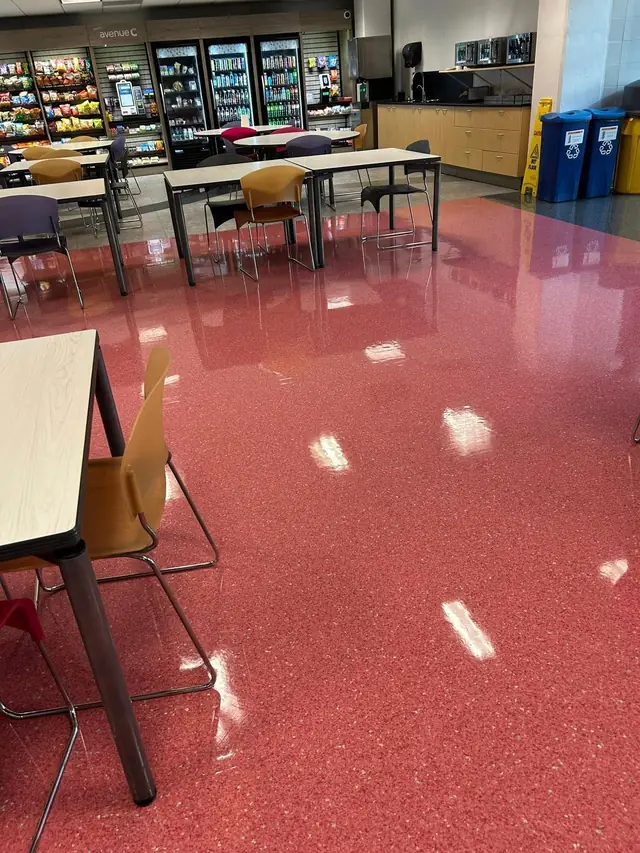 A cafeteria and break area with a red terrazzo floor, vending machines and recycling bins