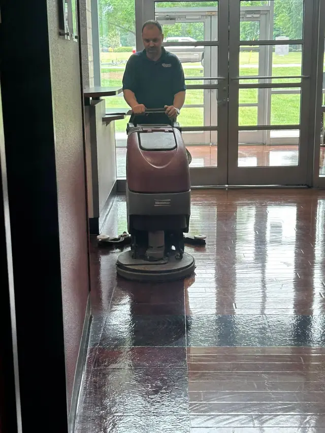 A technician running a carpet extractor across a glass fronted entrance lobby